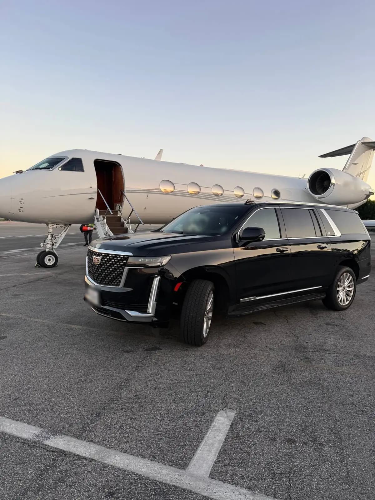 Black Cadillac Escalade beside a private jet at Van Nuys Airport